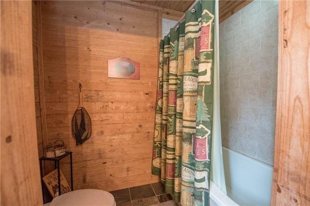 bathroom featuring tile flooring, wood walls, toilet, wooden ceiling, and shower / bath combo with shower curtain