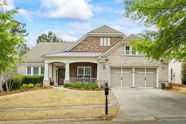 craftsman inspired home featuring a porch, driveway, a standing seam roof, brick siding, and a front yard