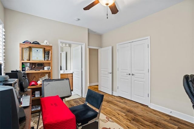 office space featuring a ceiling fan, light wood-style floors, and baseboards
