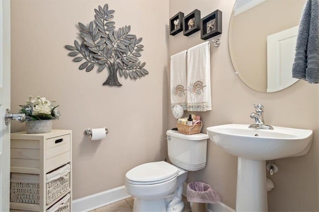 half bath with toilet, baseboards, and tile patterned floors