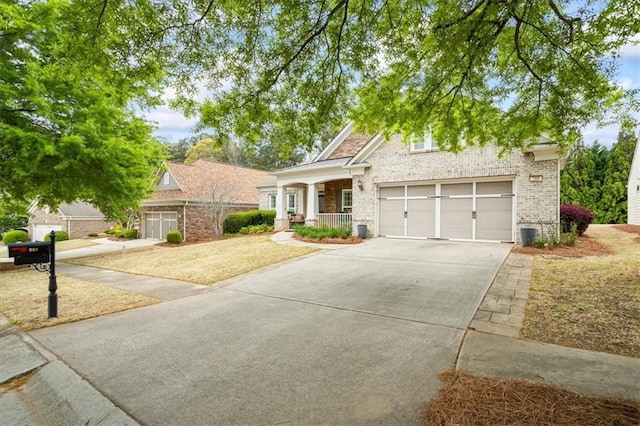 view of front facade with brick siding, driveway, a porch, a front lawn, and an attached garage