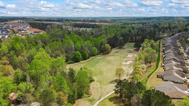 view of property location with nearby suburban area, a heavily wooded area, and a local golf course