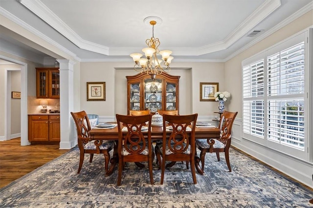 dining space with a chandelier, dark wood-type flooring, ornamental molding, and baseboards