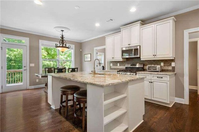 kitchen featuring appliances with stainless steel finishes, white cabinetry, a kitchen island with sink, and sink