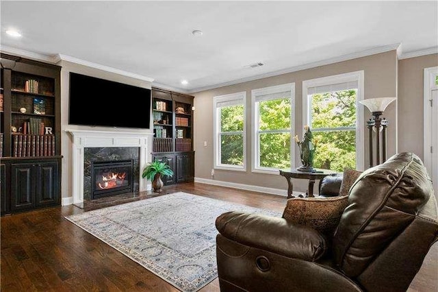 living room featuring built in features, wood-type flooring, a premium fireplace, and crown molding