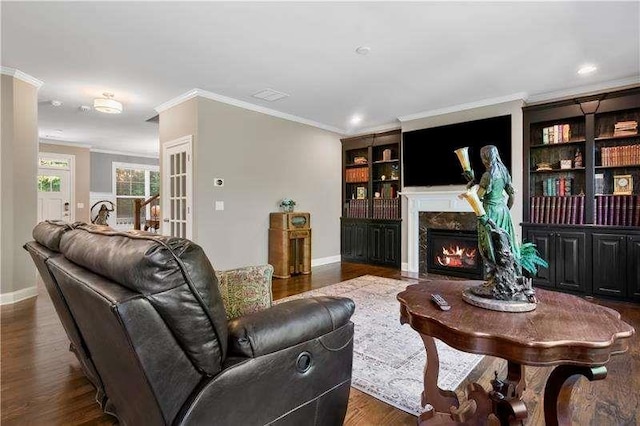 living room featuring a high end fireplace, french doors, crown molding, built in features, and dark hardwood / wood-style flooring