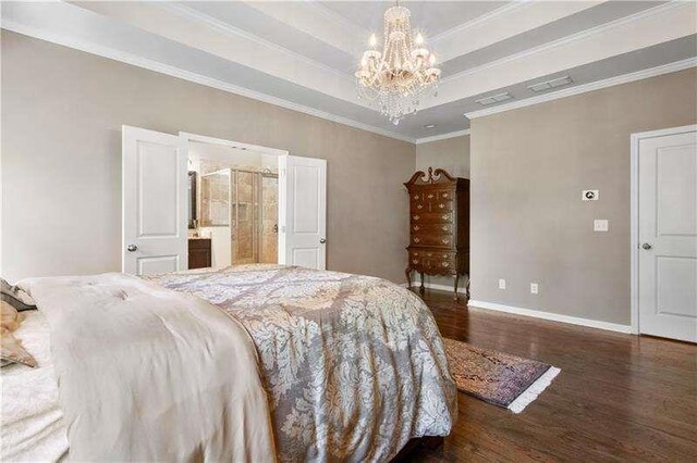 bedroom featuring ensuite bath, dark wood-type flooring, crown molding, a chandelier, and a tray ceiling