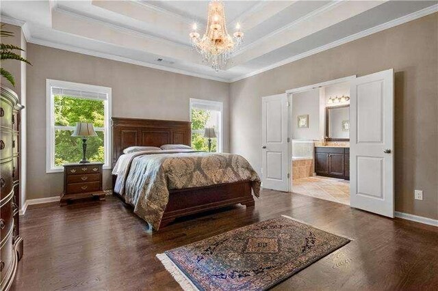 bedroom featuring connected bathroom, an inviting chandelier, a raised ceiling, hardwood / wood-style floors, and ornamental molding