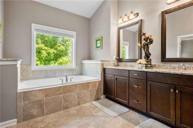 bathroom featuring tile patterned flooring, vanity, and tiled bath