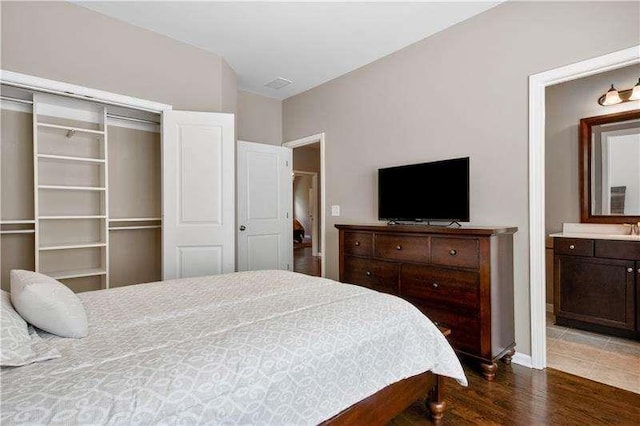 bedroom with ensuite bath, dark wood-type flooring, and a closet