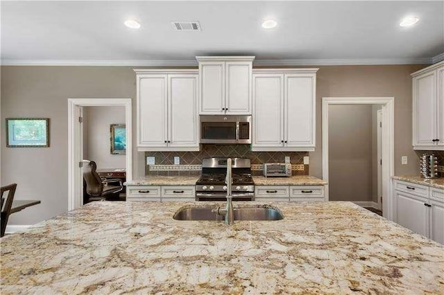 kitchen featuring appliances with stainless steel finishes, backsplash, white cabinetry, and light stone counters