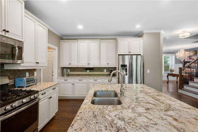 kitchen with light stone countertops, stainless steel appliances, white cabinetry, and sink