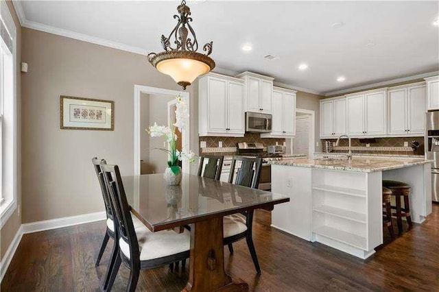 kitchen with a kitchen island with sink, dark wood-type flooring, hanging light fixtures, appliances with stainless steel finishes, and light stone counters