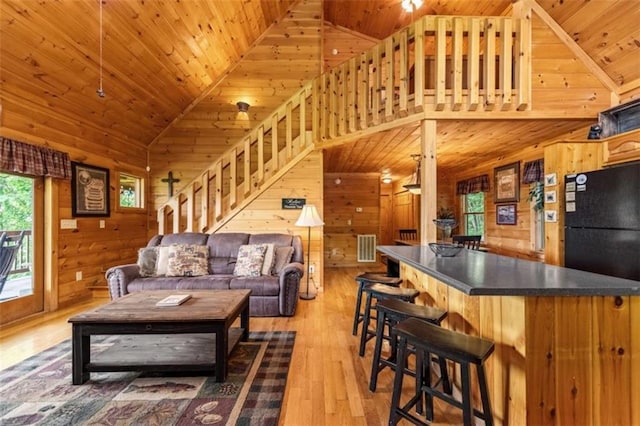 living area with light wood-type flooring, wood walls, stairway, wood ceiling, and high vaulted ceiling