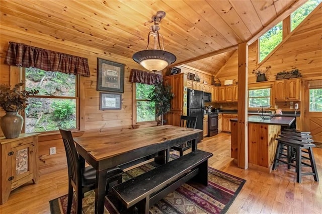 dining room with wood ceiling, lofted ceiling, light wood-style floors, and wooden walls