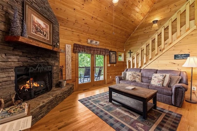 living room featuring high vaulted ceiling, wood finished floors, a fireplace, wooden ceiling, and wood walls