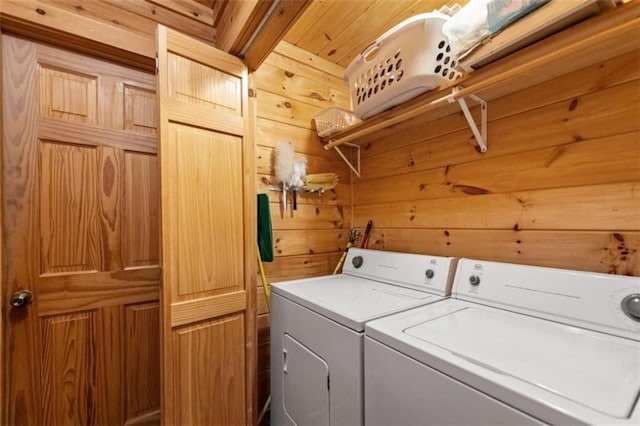 laundry area with wood walls, washer and clothes dryer, and laundry area