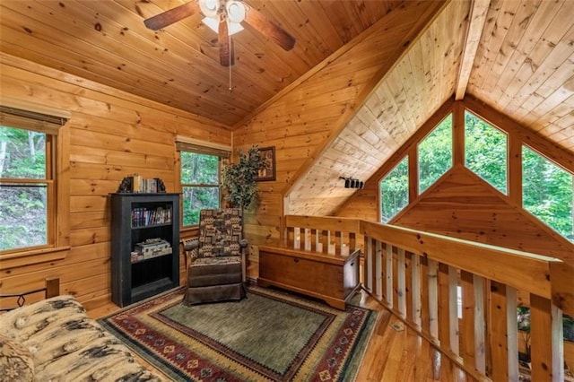 living area with lofted ceiling, hardwood / wood-style floors, wood walls, wood ceiling, and ceiling fan