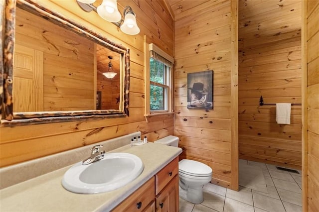 bathroom with tile patterned flooring, wooden walls, toilet, and vanity