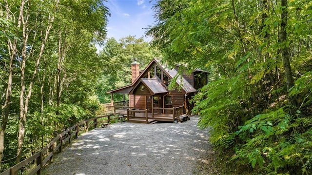 exterior space with a chimney, gravel driveway, and a wooden deck