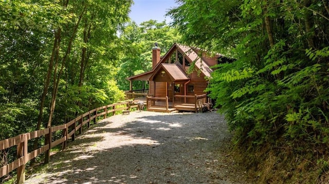 view of side of home with a chimney, driveway, and a deck