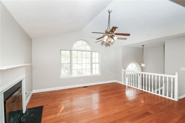 unfurnished living room with wood-type flooring, vaulted ceiling, ceiling fan, and a healthy amount of sunlight