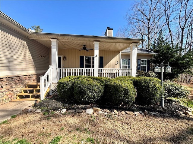 doorway to property with a porch, a chimney, and ceiling fan