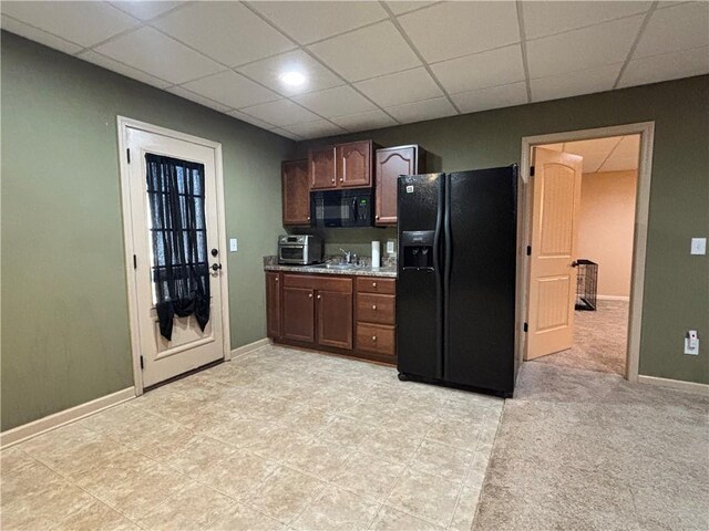 kitchen with black appliances, a paneled ceiling, and baseboards