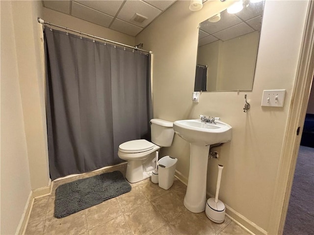 bathroom with a shower with curtain, baseboards, a drop ceiling, tile patterned floors, and toilet