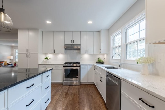 kitchen with tasteful backsplash, hanging light fixtures, light stone counters, dark hardwood / wood-style floors, and appliances with stainless steel finishes