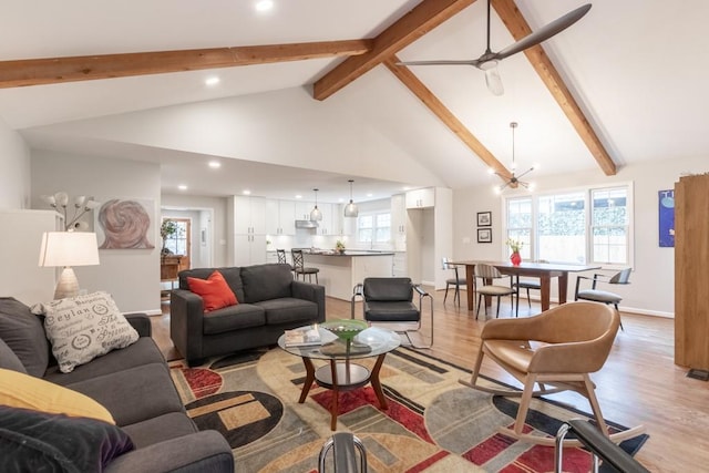 living room featuring high vaulted ceiling, beam ceiling, ceiling fan with notable chandelier, and light wood-type flooring