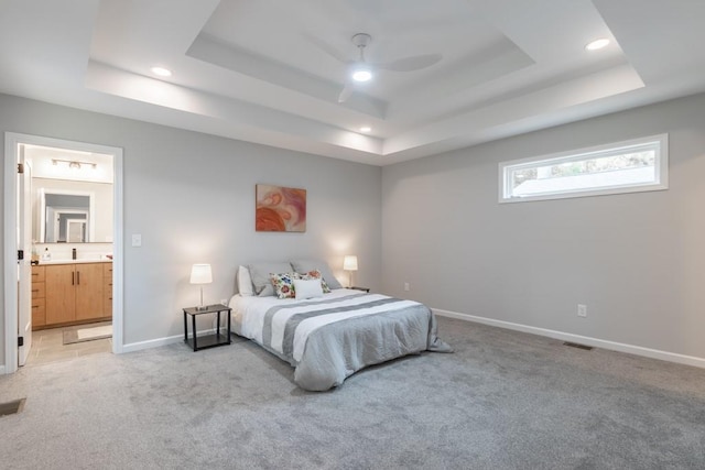 carpeted bedroom with ensuite bath, ceiling fan, and a raised ceiling