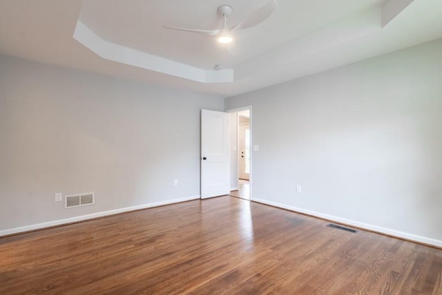 spare room featuring ceiling fan, a tray ceiling, and hardwood / wood-style floors