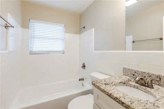 full bathroom with tiled shower / bath, tile walls, vanity, and toilet