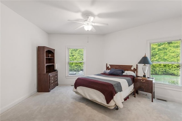 carpeted bedroom featuring multiple windows and ceiling fan