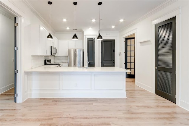 kitchen with sink, white cabinetry, hanging light fixtures, appliances with stainless steel finishes, and kitchen peninsula