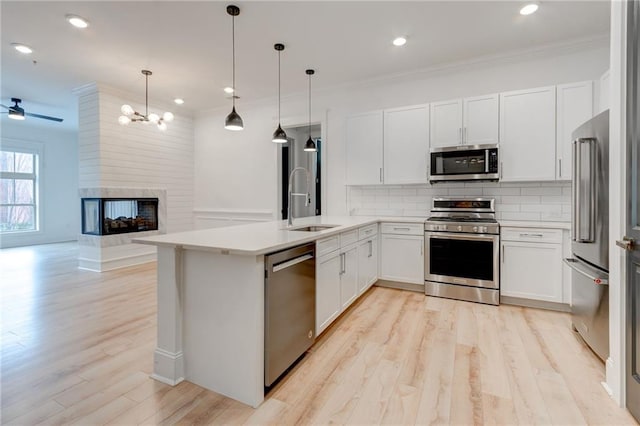 kitchen featuring appliances with stainless steel finishes, pendant lighting, sink, white cabinets, and kitchen peninsula