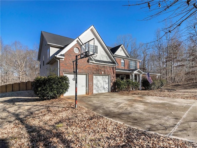 view of side of home featuring a garage, fence, brick siding, and driveway