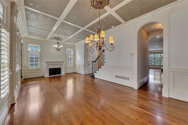 4853 Stonehall Pl, Atlanta, GA 30339 - unfurnished living room with a chandelier, coffered ceiling, wood finished floors, a premium fireplace, and arched walkways
