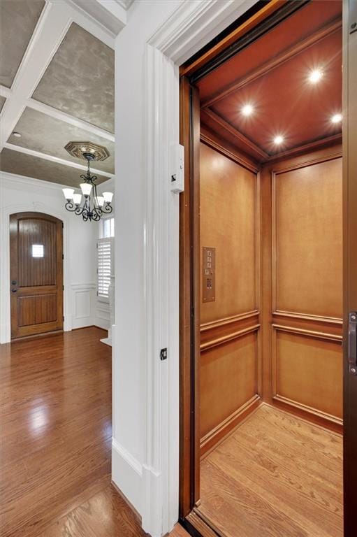 4853 Stonehall Pl, Atlanta, GA 30339 - elevator featuring a decorative wall, wood finished floors, a chandelier, coffered ceiling, and beam ceiling