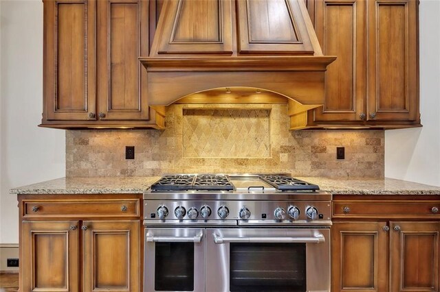 4853 Stonehall Pl, Atlanta, GA 30339 - kitchen featuring high end stove, brown cabinetry, backsplash, and light stone counters
