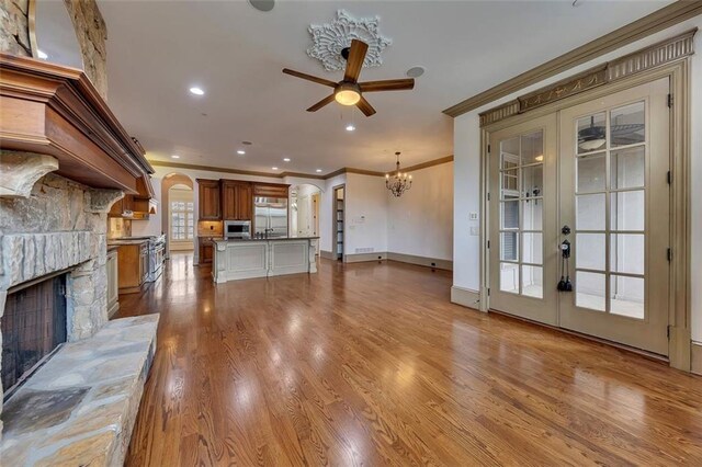 4853 Stonehall Pl, Atlanta, GA 30339 - unfurnished living room featuring crown molding, french doors, arched walkways, a ceiling fan, and a stone fireplace