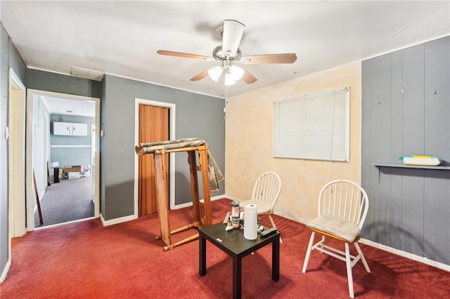 living area featuring a ceiling fan, baseboards, and carpet