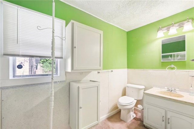 bathroom featuring vanity, a textured ceiling, a wainscoted wall, and toilet