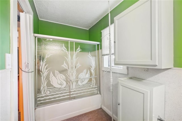 bathroom featuring bath / shower combo with glass door and a textured ceiling