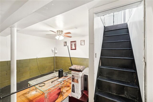 stairway featuring a ceiling fan
