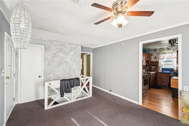carpeted spare room featuring a sink, a ceiling fan, a textured ceiling, and baseboards