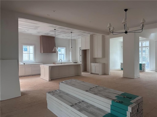 kitchen featuring white cabinetry, sink, a center island, and pendant lighting