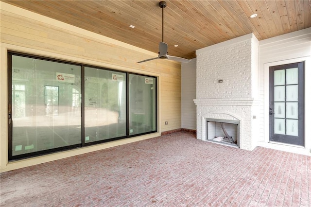 unfurnished living room with ceiling fan, wooden ceiling, a fireplace, and wood walls