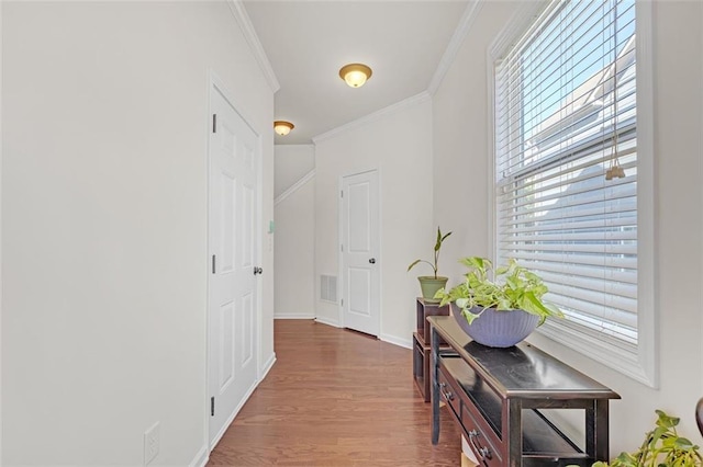 hallway with visible vents, crown molding, baseboards, and wood finished floors